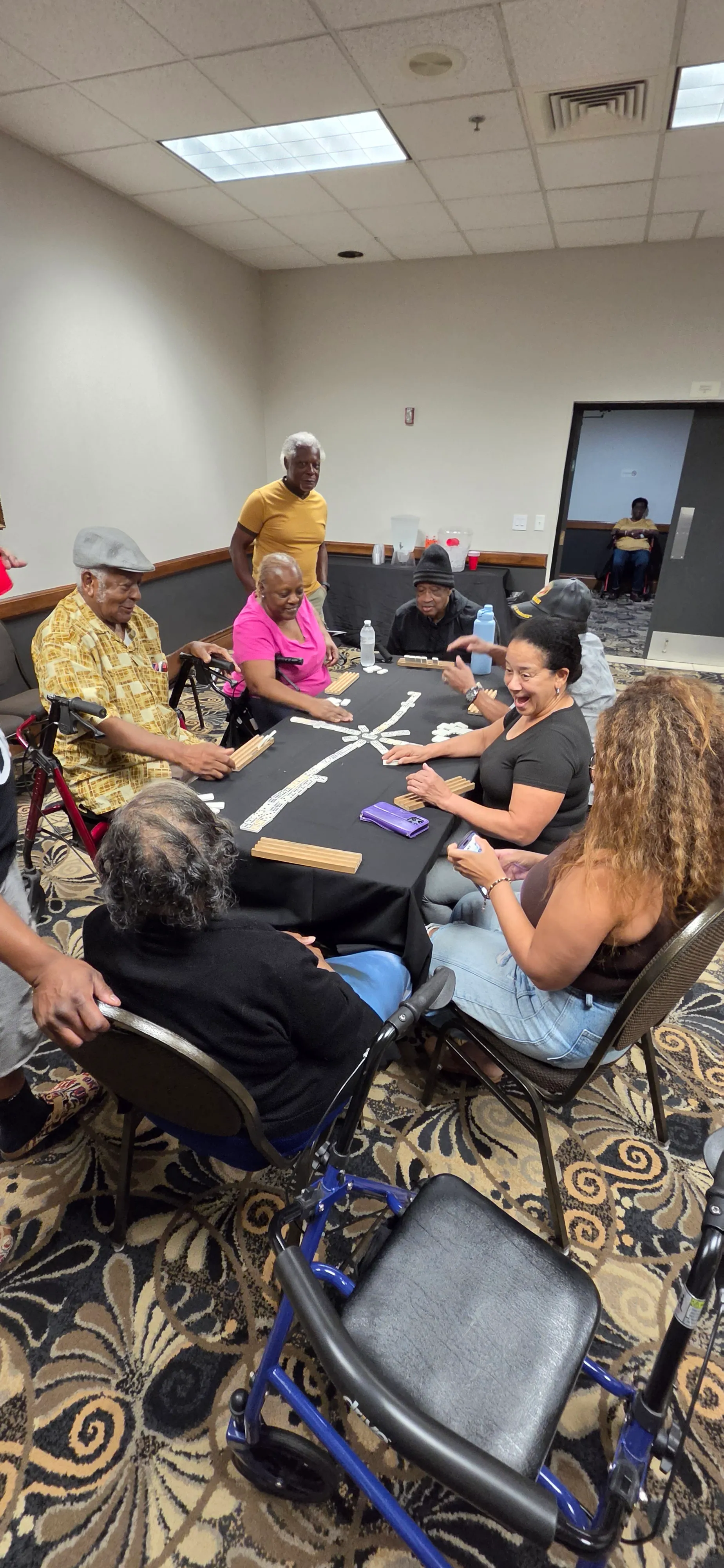 Relatives of different ages around a game table in a hotel meeting room.
