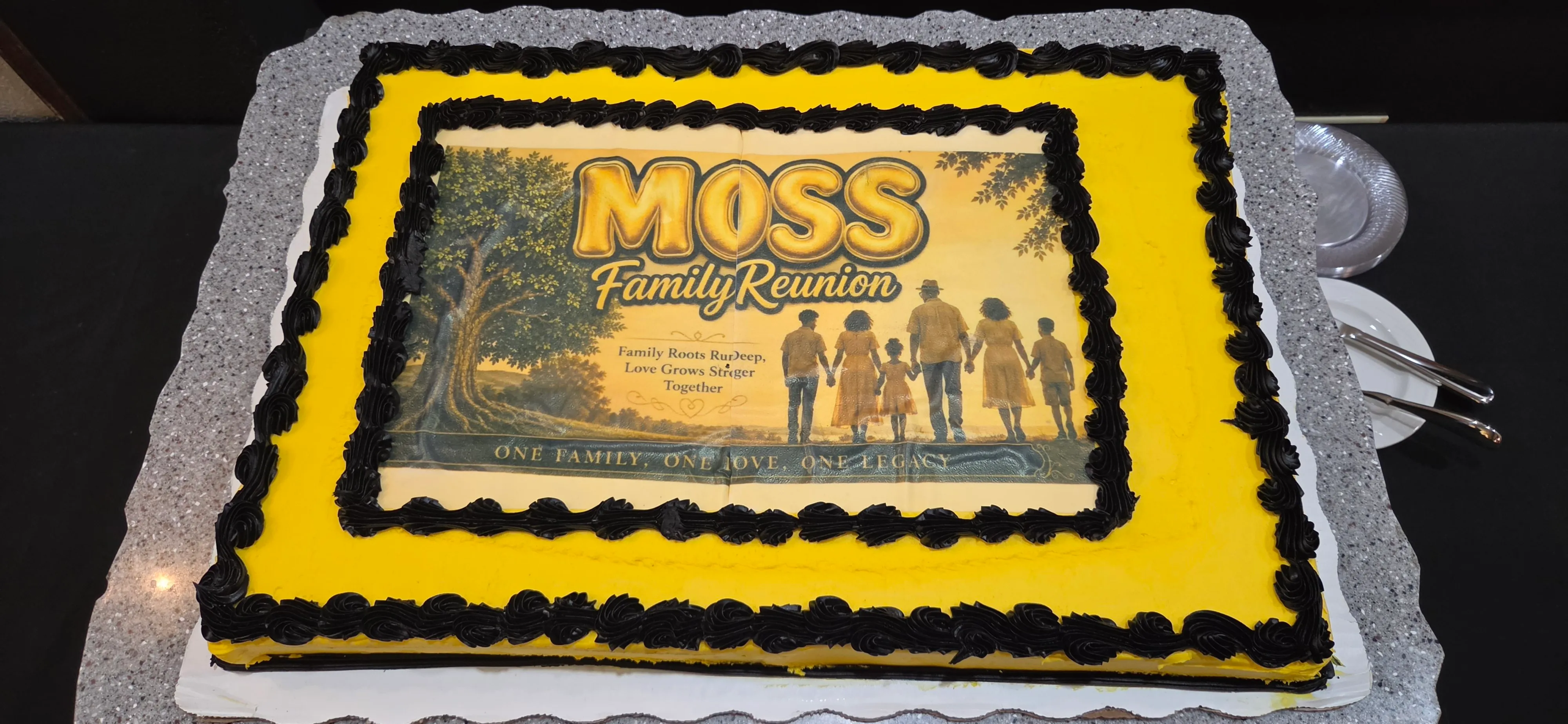 A yellow sheet cake with black trim and the Moss Family Reunion artwork on top.